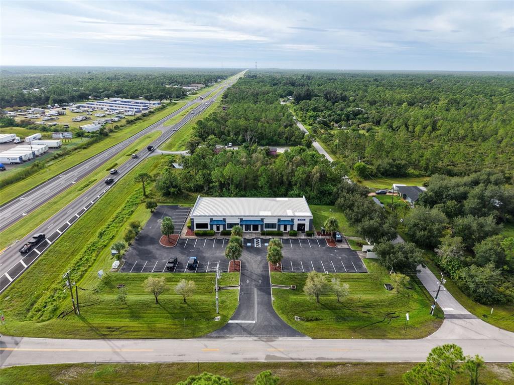 An aerial view shows a commercial building with a parking lot next to a highway — 29291 TRIBUNE BOULEVARD UNIT 4-109, PUNTA GORDA, FL