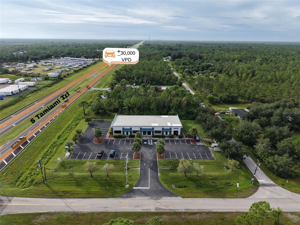 An aerial view shows a commercial building with a parking lot next to a highway — 29291 TRIBUNE BOULEVARD UNIT 4-109, PUNTA GORDA, FL