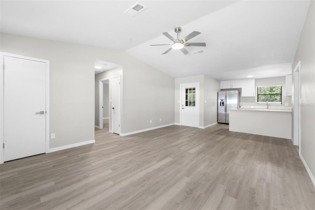 A bright, open-concept living room with light gray walls, wood-look flooring, and a ceiling fan — 2329 NW 54TH PLACE, GAINESVILLE, FL