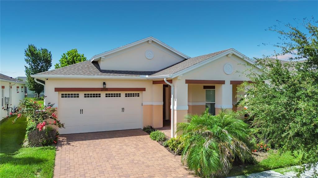 A single-story house with a beige stucco exterior, a two-car garage, and a paved driveway — 2720 GREENLANDS STREET, ST CLOUD, FL