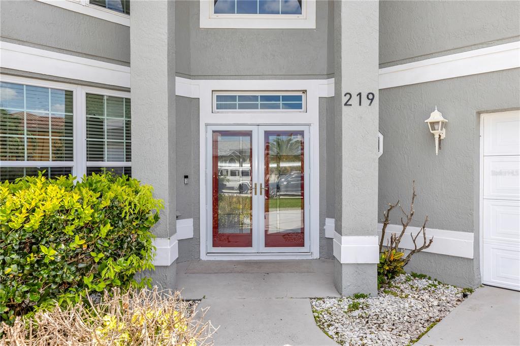 The exterior entrance features double glass doors, a gray facade, and a small gravel garden — 219 STRATHMORE CIRCLE, KISSIMMEE, FL
