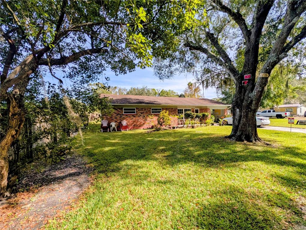 A single-story brick house sits on a grassy lot shaded by large, mature trees — 8410 PETERSON ROAD, ODESSA, FL