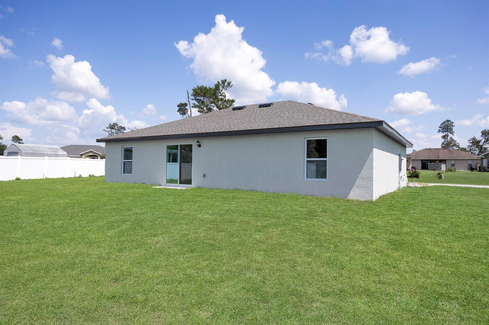The exterior of a single-story house with a large grassy backyard and white fence — 8045 105th Court, Vero Beach FL 32967, VERO BEACH, FL