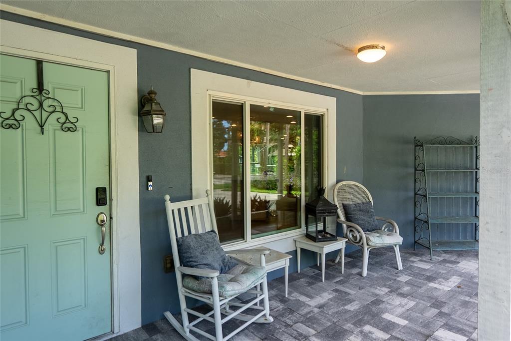 A covered front porch features a light blue door, two chairs, and a metal shelf — 3140 BAY SHORE ROAD, SARASOTA, FL