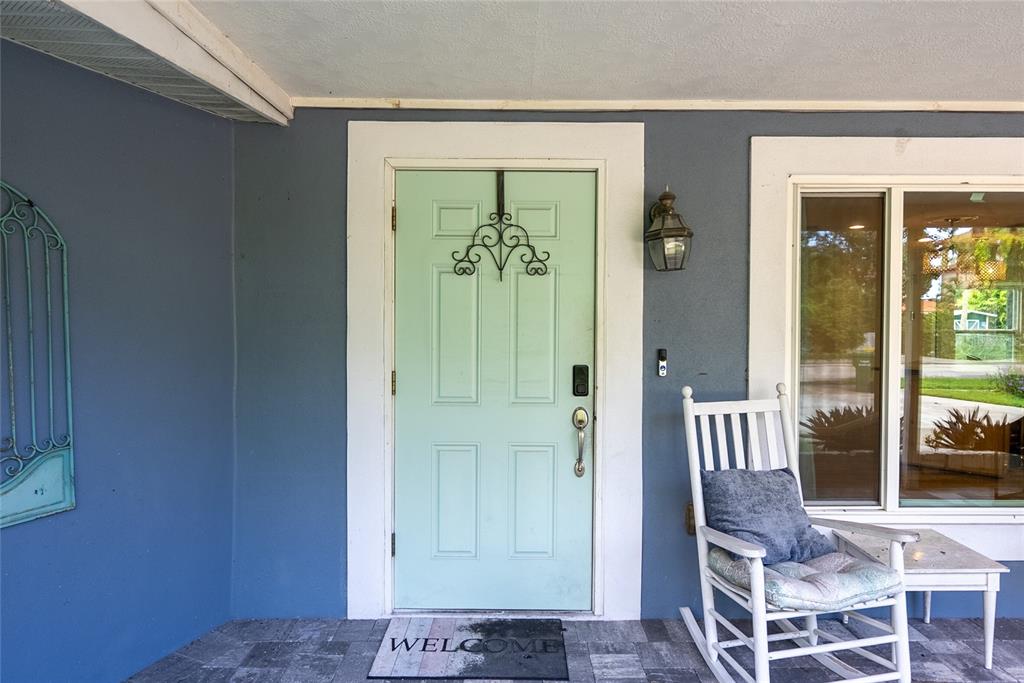 A light green front door with a rocking chair sits on a covered porch — 3140 BAY SHORE ROAD, SARASOTA, FL