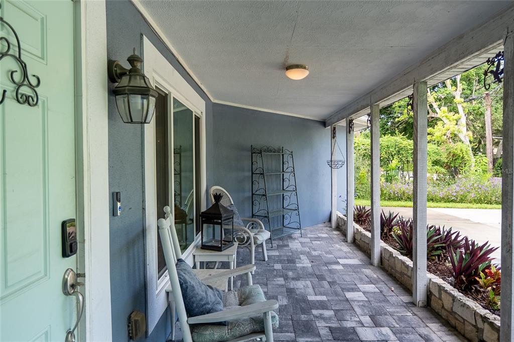 A covered front porch features a light blue door, rocking chairs, and stone paver flooring — 3140 BAY SHORE ROAD, SARASOTA, FL