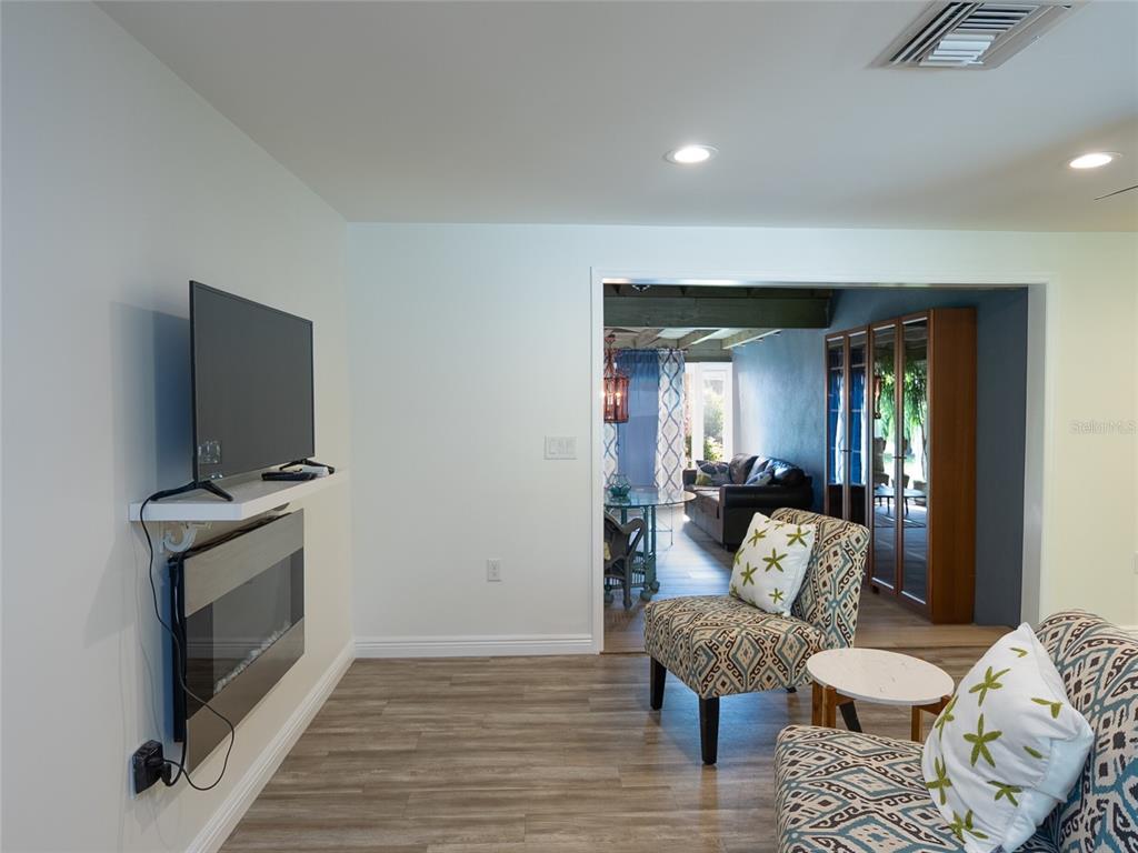 A living room features a wall-mounted television, an electric fireplace, and patterned armchairs — 3140 BAY SHORE ROAD, SARASOTA, FL