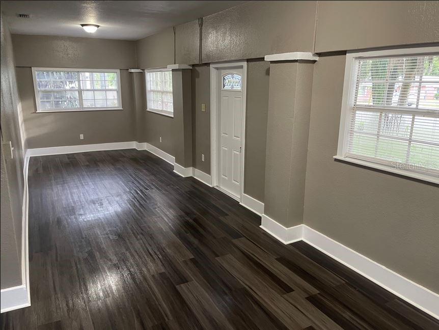 An empty room with dark wood-look flooring, gray walls, white trim, and several windows — 590 S BROADWAY AVENUE, BARTOW, FL