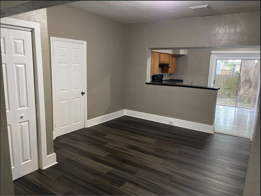 A room with dark wood-look flooring, gray walls, two white doors, and a kitchen pass-through — 590 S BROADWAY AVENUE, BARTOW, FL