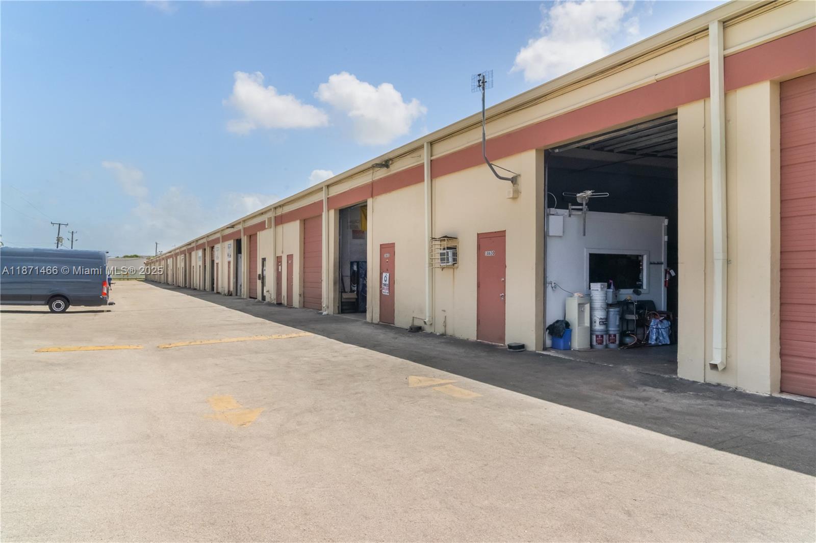 An exterior view of a long commercial warehouse building with multiple roll-up doors and pedestrian entrances — 18625 SW 105 AV, Miami FL 33157, MIAMI, FL