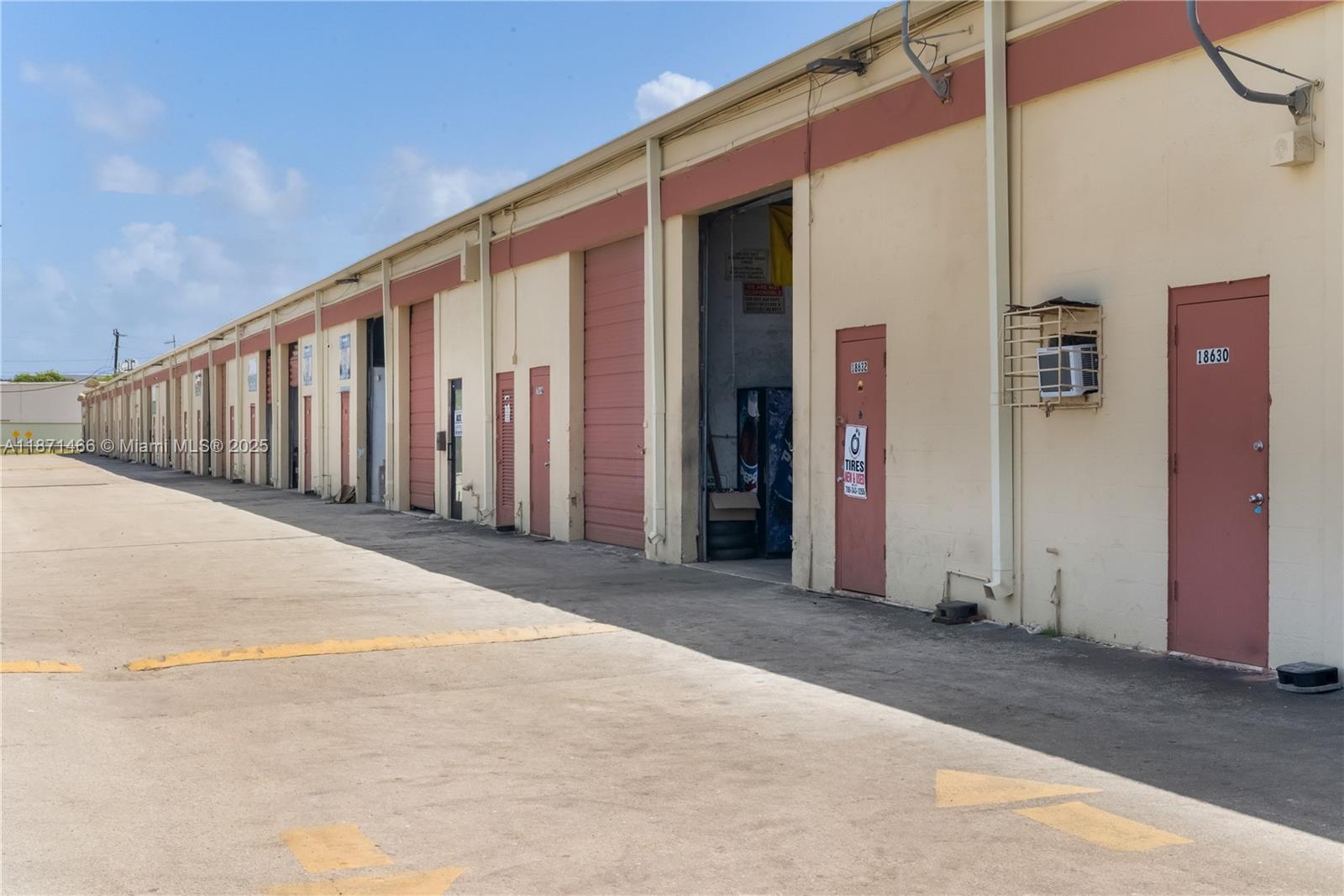 An exterior view of a long commercial warehouse building with multiple roll-up and pedestrian doors — 18625 SW 105 AV, Miami FL 33157, MIAMI, FL