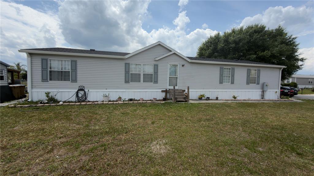 A single-story manufactured home with light gray siding and a front entrance with steps — 306 EVANDEE COURT, KISSIMMEE, FL