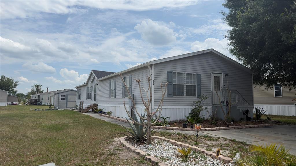 A single-story manufactured home with grey siding, a concrete driveway, and a small storage shed — 306 EVANDEE COURT, KISSIMMEE, FL