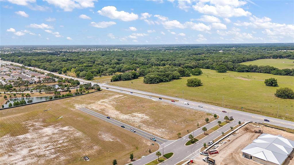 An aerial view shows a vacant lot near a road, a pond, and residential development — CR 466A / MILLER BOULEVARD UNIT #B & #C, FRUITLAND PARK, FL
