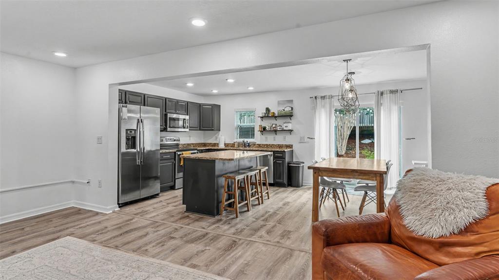 A kitchen with dark cabinets, granite countertops, and an island opens to a dining area — 3806 EXETER LANE, LAKELAND, FL