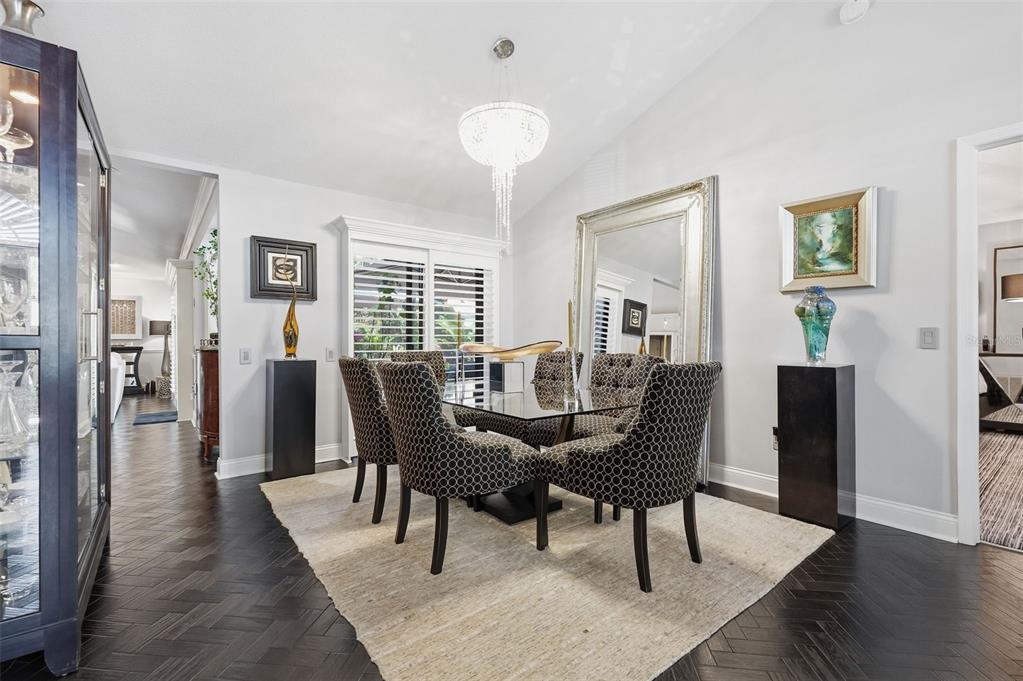 A dining room features a glass table, patterned chairs, a large mirror, and dark flooring — 11760 ASHLEY COURT, SEMINOLE, FL