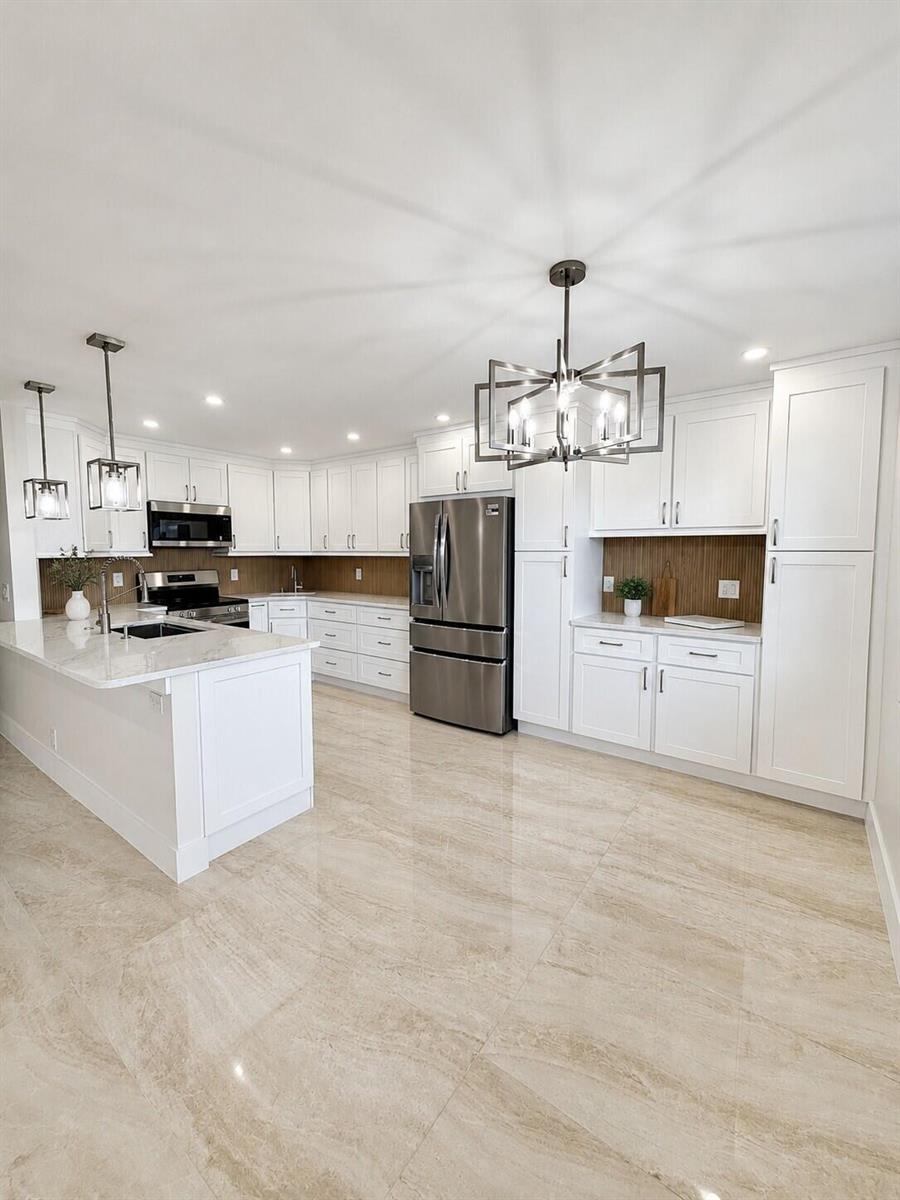 A modern kitchen features white cabinetry, stainless steel appliances, a marble island, and tile flooring — 4047 Ainslie C # 4047, Boca Raton FL 33434, BOCA RATON, FL