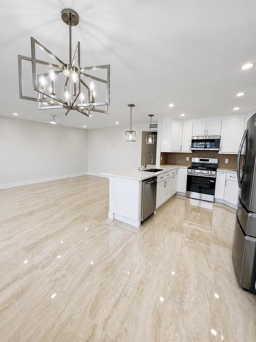 A modern kitchen with white cabinets, stainless steel appliances, and polished tile flooring — 4047 Ainslie C # 4047, Boca Raton FL 33434, BOCA RATON, FL