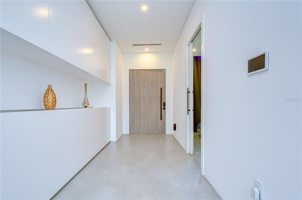 A minimalist hallway features white cabinetry, a slatted wood door, and a glass-paneled doorway — 6805 NEW YORK DRIVE, TAMPA, FL