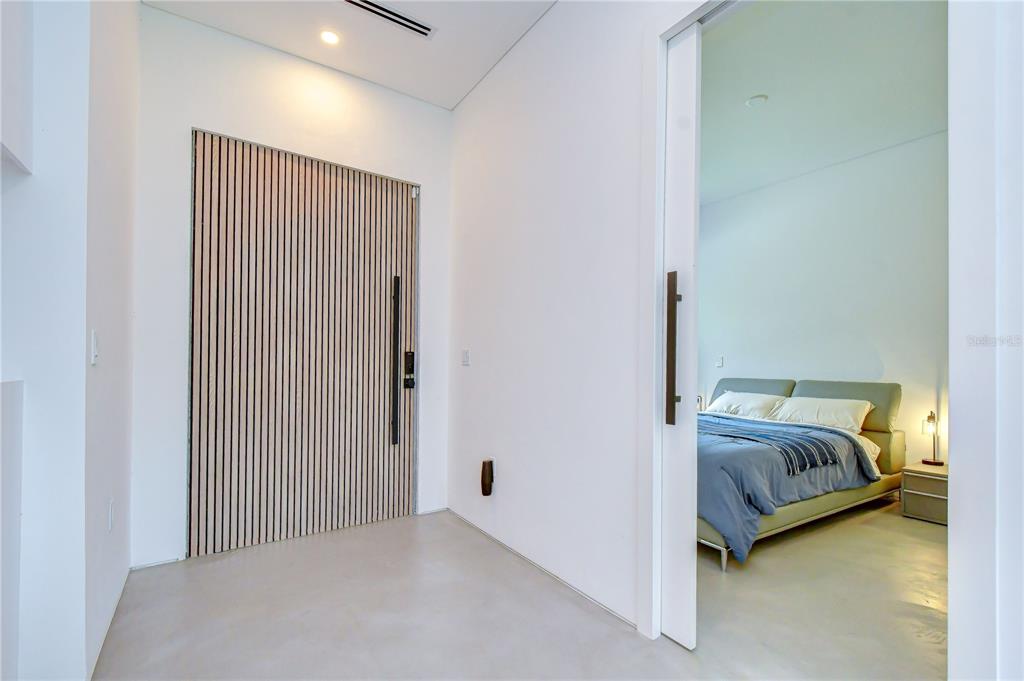 A modern entryway features a slatted wood door and a sliding door leading to a bedroom — 6805 NEW YORK DRIVE, TAMPA, FL