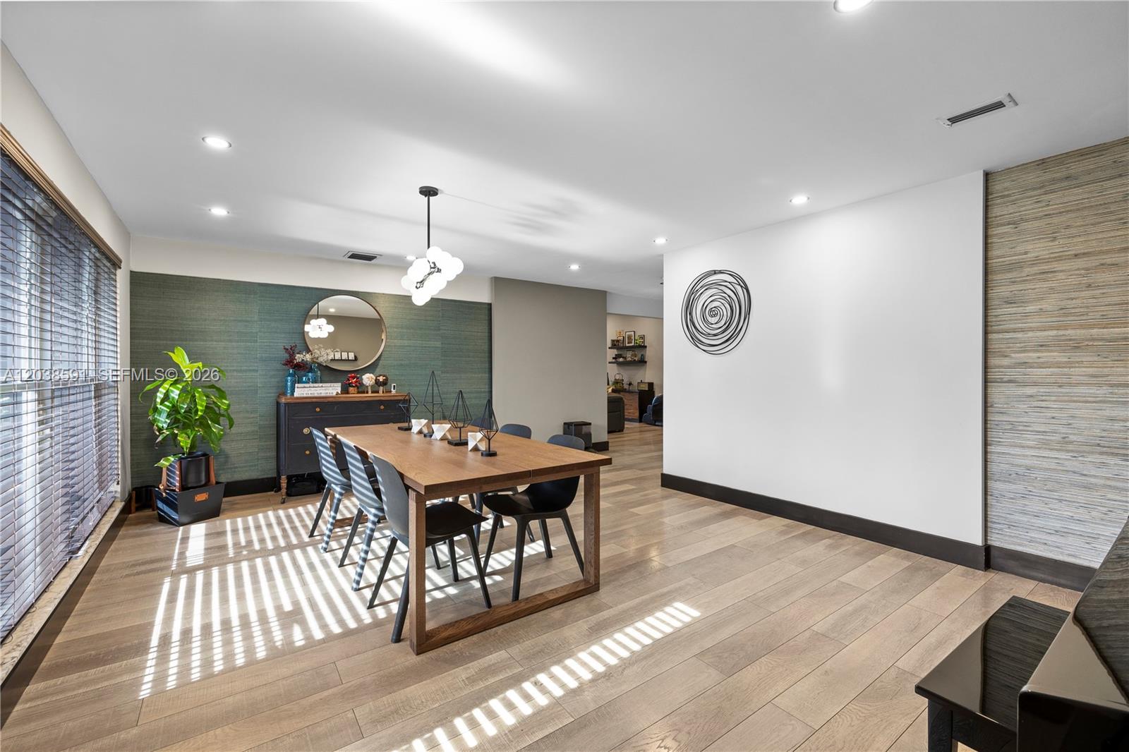 A dining room features a wooden table, modern chairs, textured wallpaper, and recessed lighting — DAVIE, FL