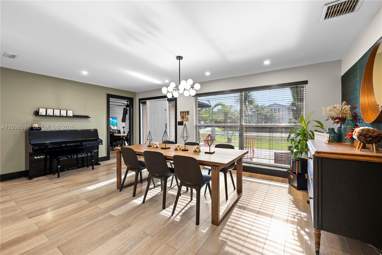 A dining room features a wooden table, black chairs, a piano, and large windows — DAVIE, FL
