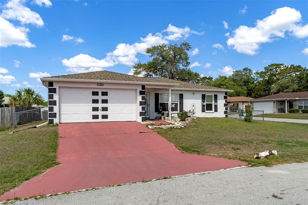 A single-story house with a white exterior, a red driveway, and a two-car garage — 3786 S GREY DOVE TERRACE, HOMOSASSA, FL