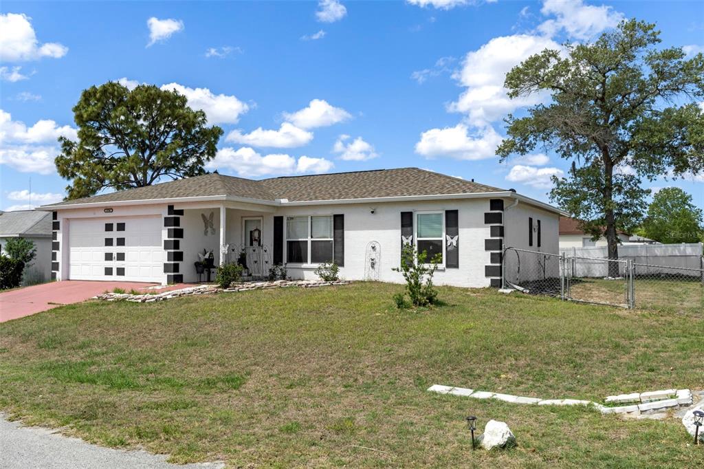 A single-story white house with a two-car garage and a large front yard — 3786 S GREY DOVE TERRACE, HOMOSASSA, FL