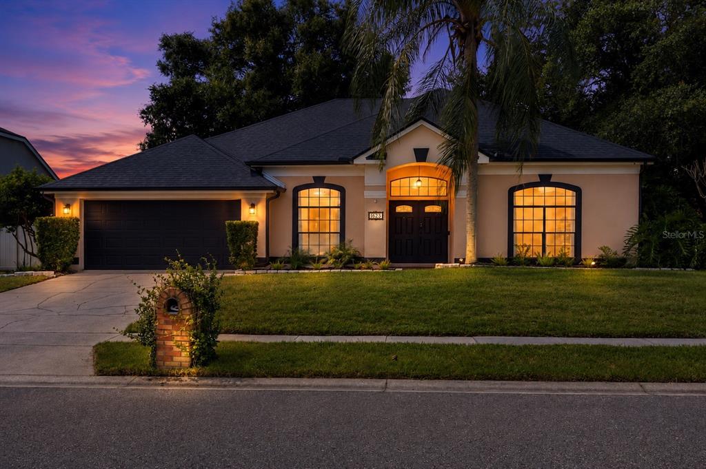 A single-story house with a dark garage, arched windows, and a brick mailbox at dusk — 623 YORKSHIRE DRIVE, OVIEDO, FL