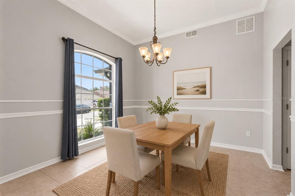 A dining room features a wooden table, four upholstered chairs, a chandelier, and a window — 623 YORKSHIRE DRIVE, OVIEDO, FL