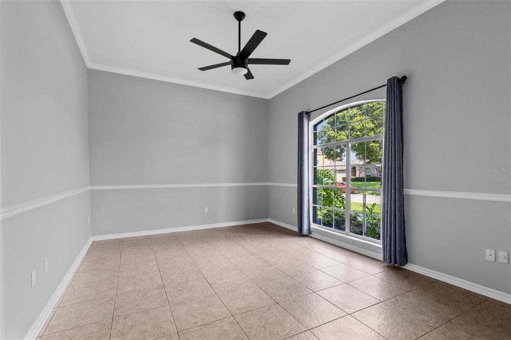 An empty room with light gray walls, white chair rail molding, tile flooring, and arched window — 623 YORKSHIRE DRIVE, OVIEDO, FL