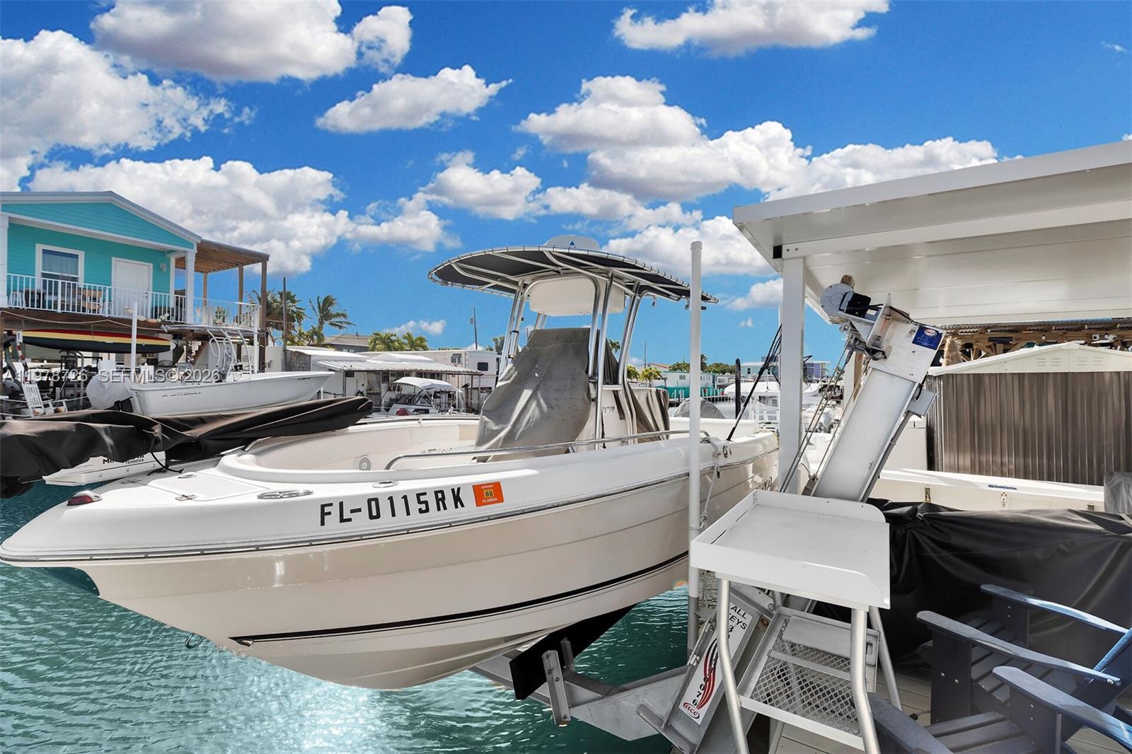 A white center console boat is docked on a lift in a canal — 6099 Overseas Hwy 55W, Marathon FL 33050, MARATHON, FL