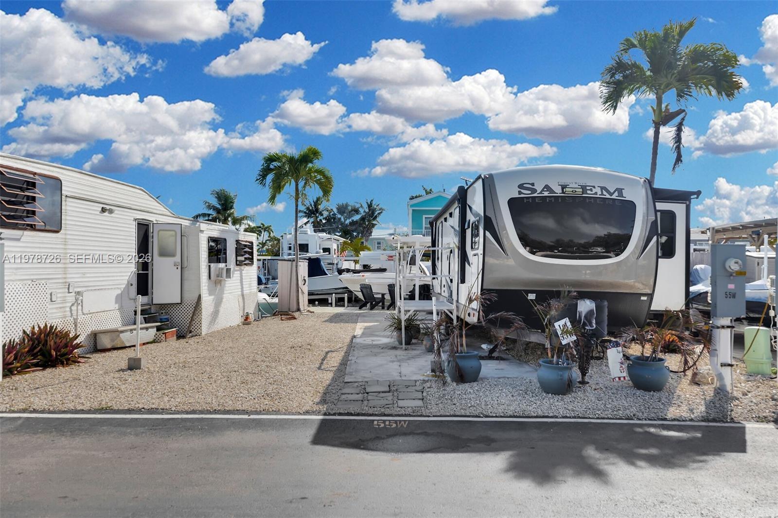 Two recreational vehicles are parked on a gravel lot with palm trees under a blue sky — 6099 Overseas Hwy 55W, Marathon FL 33050, MARATHON, FL