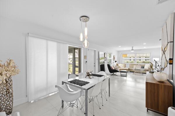 A dining area with a modern chandelier leads into a bright, open-concept living room — 10137 S 40th Way # 233, Boynton Beach FL 33436, BOYNTON BEACH, FL
