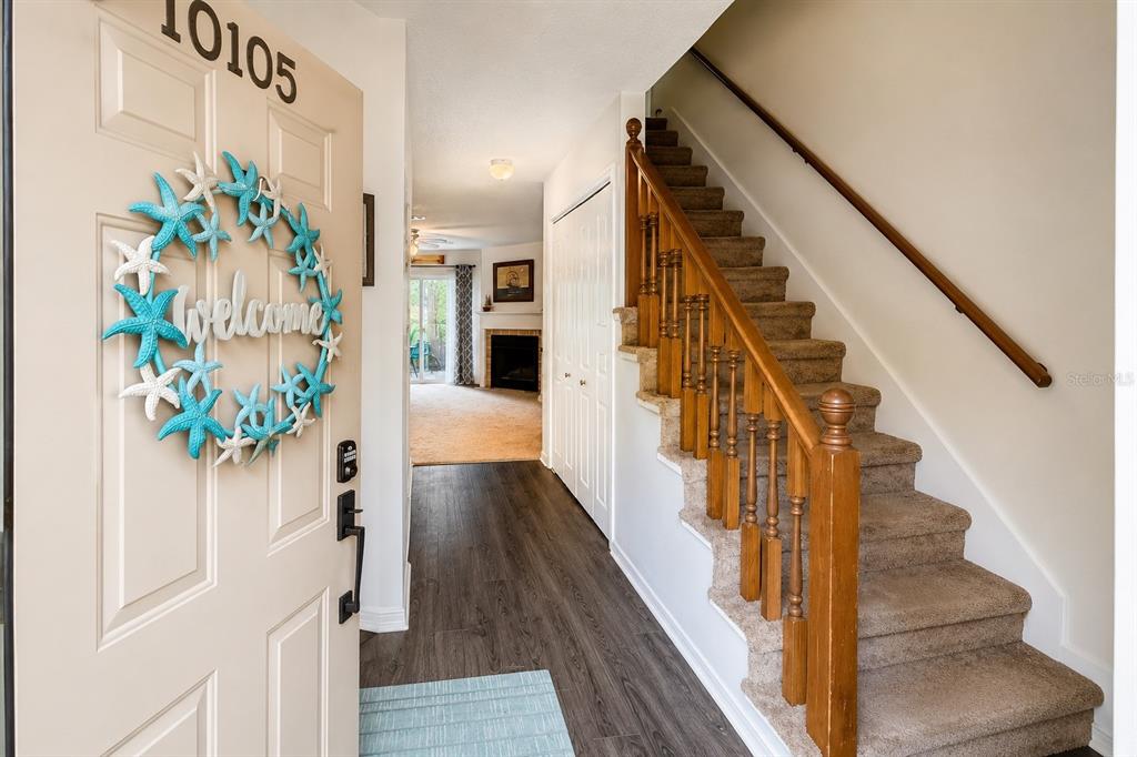 An entryway features a wood-look floor, a carpeted staircase with a wooden railing, and a door — 10105 VIXEN PLACE, PENSACOLA, FL