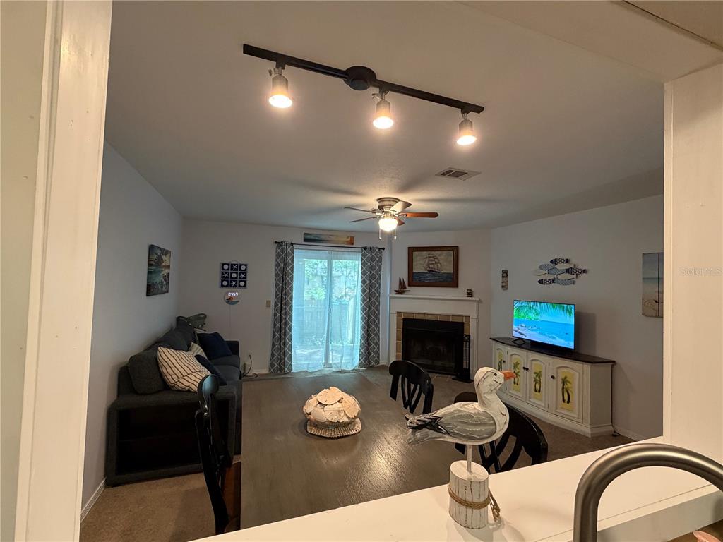 A living and dining area features a fireplace, sliding glass doors, and a ceiling fan — 10105 VIXEN PLACE, PENSACOLA, FL