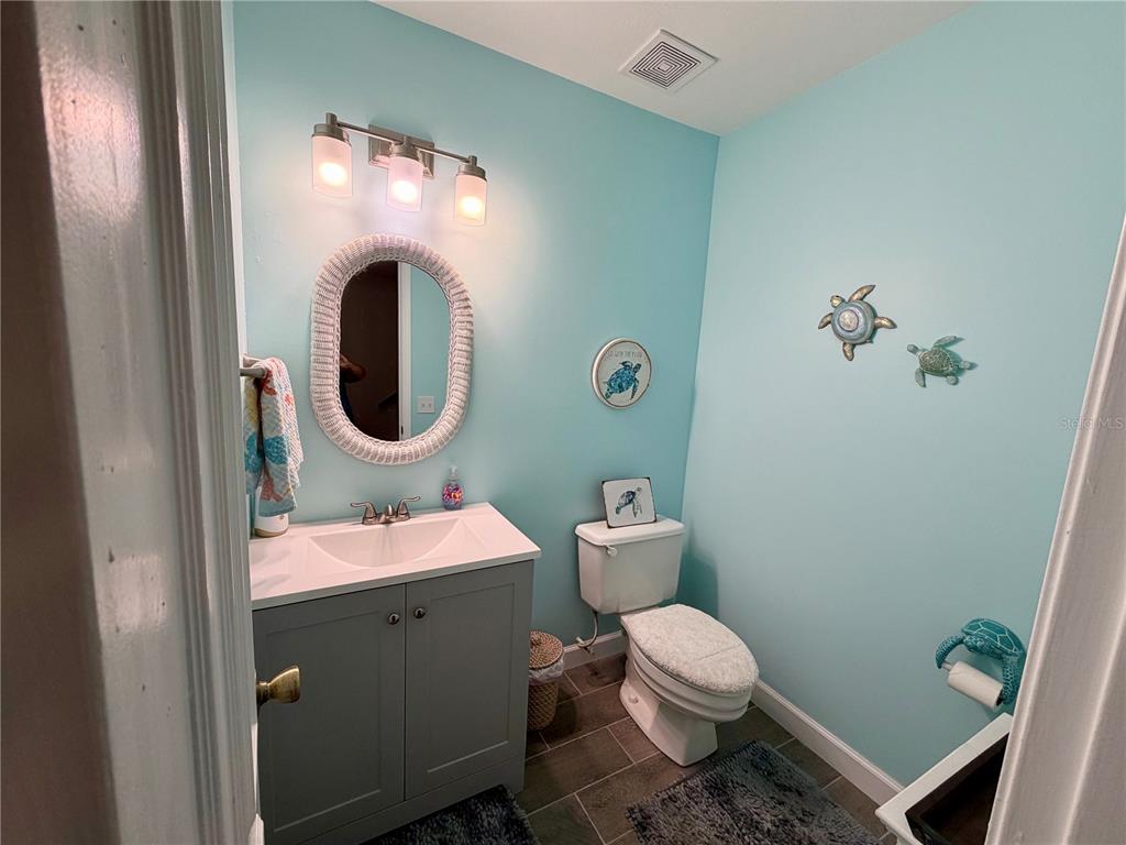 A bathroom with light blue walls, a gray vanity, a white toilet, and turtle-themed decor — 10105 VIXEN PLACE, PENSACOLA, FL