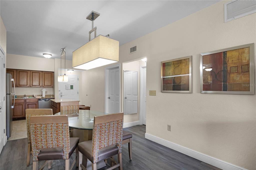 A dining area with a glass table and chairs sits adjacent to a kitchen — 12544 FLORIDAYS RESORT DRIVE UNIT 106B, ORLANDO, FL
