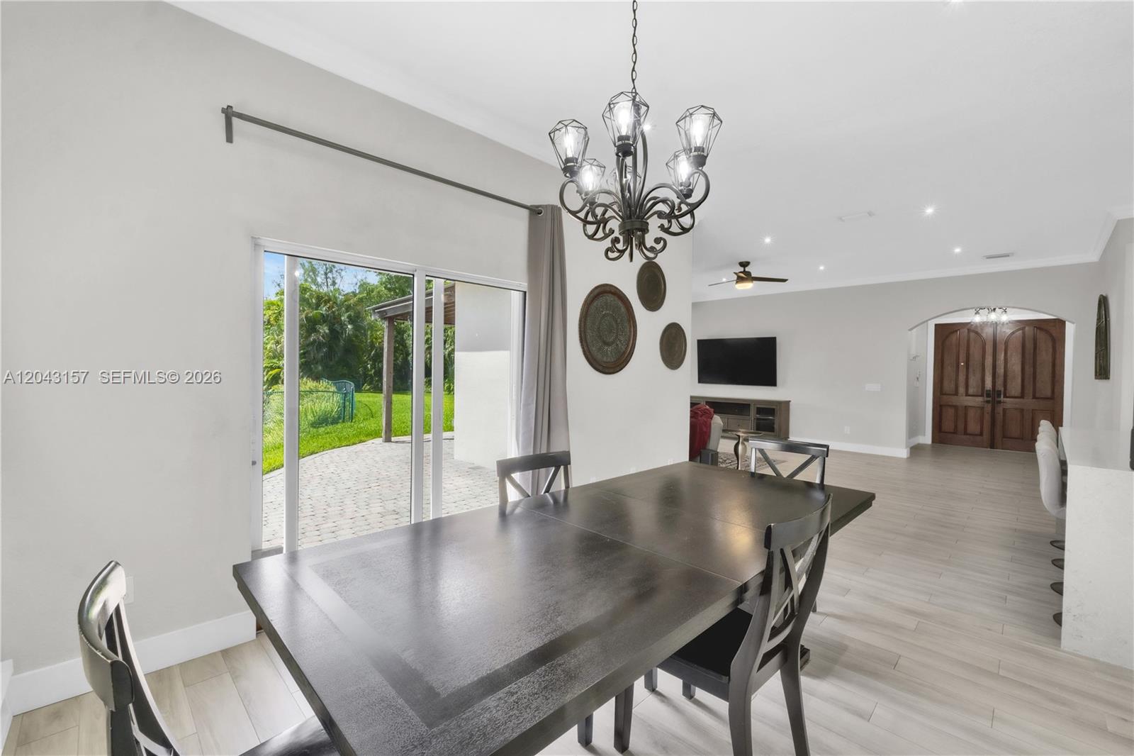 A dining area features a dark wood table, a chandelier, and sliding glass patio doors — 720 S Old Nob Hill Rd, Plantation FL 33324, PLANTATION, FL
