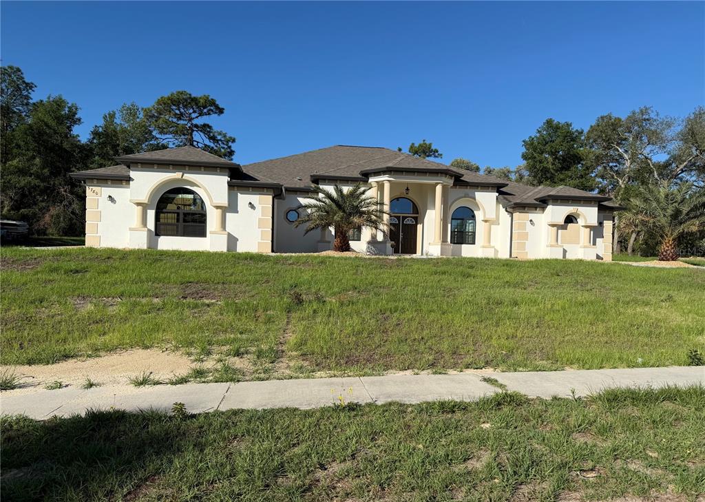 A single-story stucco house with arched windows and a central entryway sits on a grassy lot — 5780 N LENA DRIVE, BEVERLY HILLS, FL
