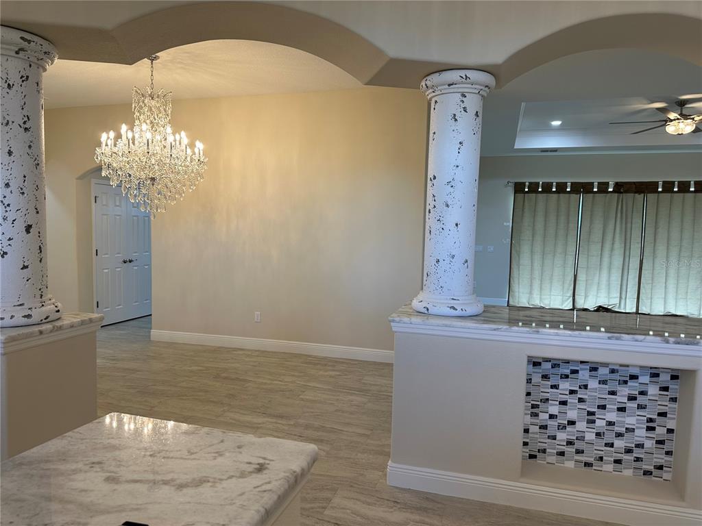 A room features a crystal chandelier, two decorative columns, and a tiled half-wall counter — 5780 N LENA DRIVE, BEVERLY HILLS, FL