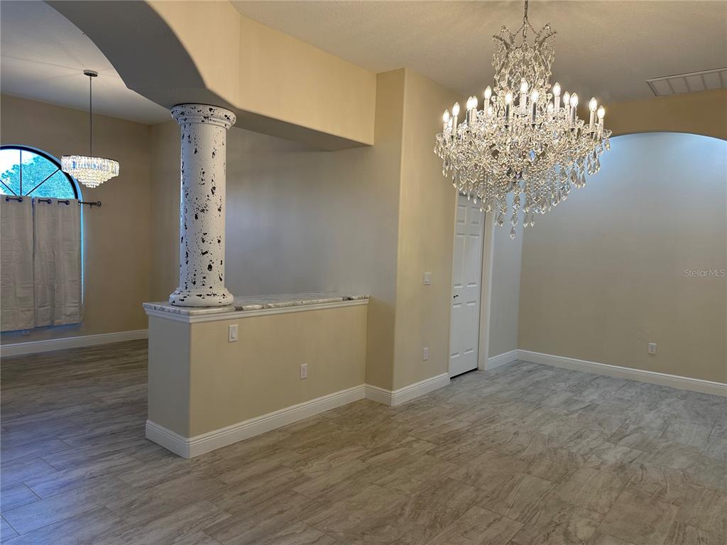 A dining area features a large crystal chandelier, a decorative column, and wood-look tile flooring — 5780 N LENA DRIVE, BEVERLY HILLS, FL