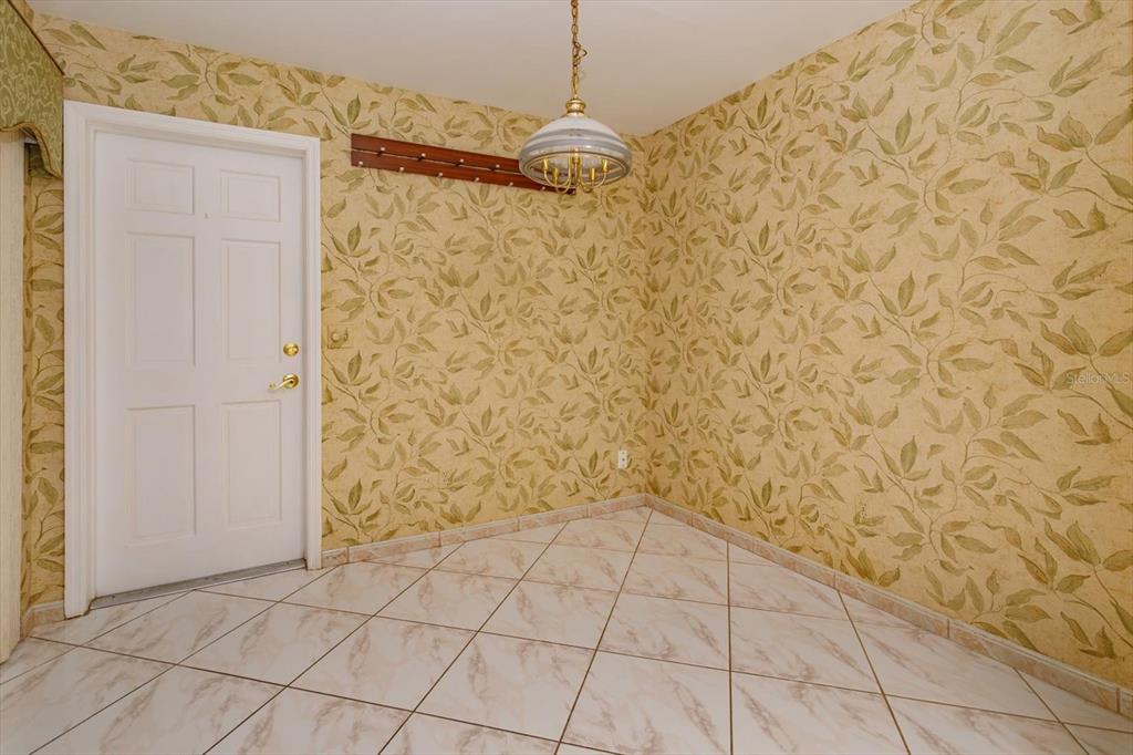 A room with beige leaf-patterned wallpaper, white tiled floors, and a hanging pendant light — 8266 AMBROSE COVE WAY, ORLANDO, FL