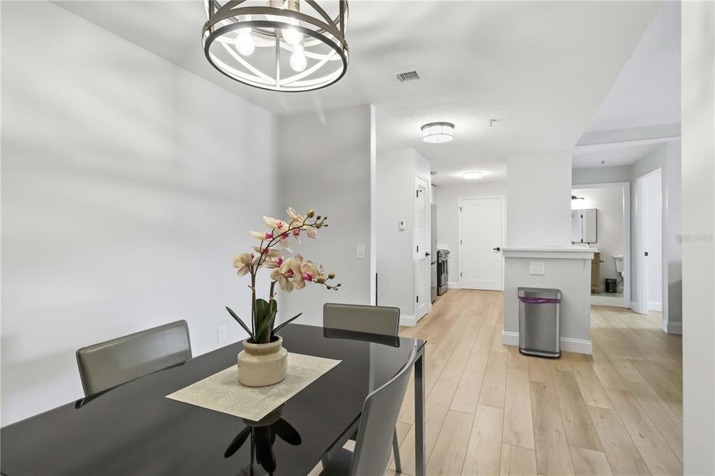 A dining area with a black table and chandelier leads into a kitchen and hallway — 750 N TAMIAMI TRAIL UNIT 312, SARASOTA, FL
