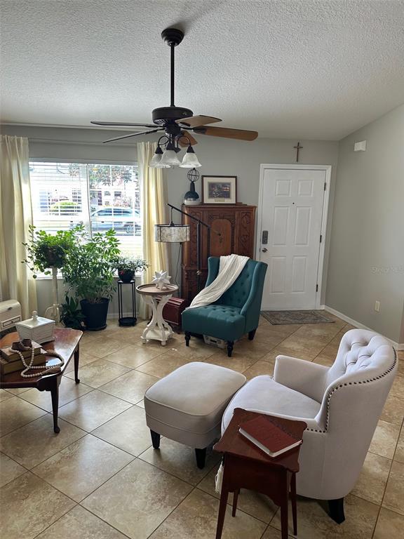A living room features tile flooring, a ceiling fan, two armchairs, and a front door — 17353 SE 76TH FLINTLOCK TERRACE, THE VILLAGES, FL
