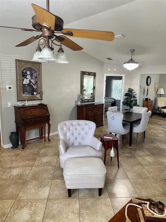 A living and dining area features tile flooring, a ceiling fan, and neutral wall paint — 17353 SE 76TH FLINTLOCK TERRACE, THE VILLAGES, FL