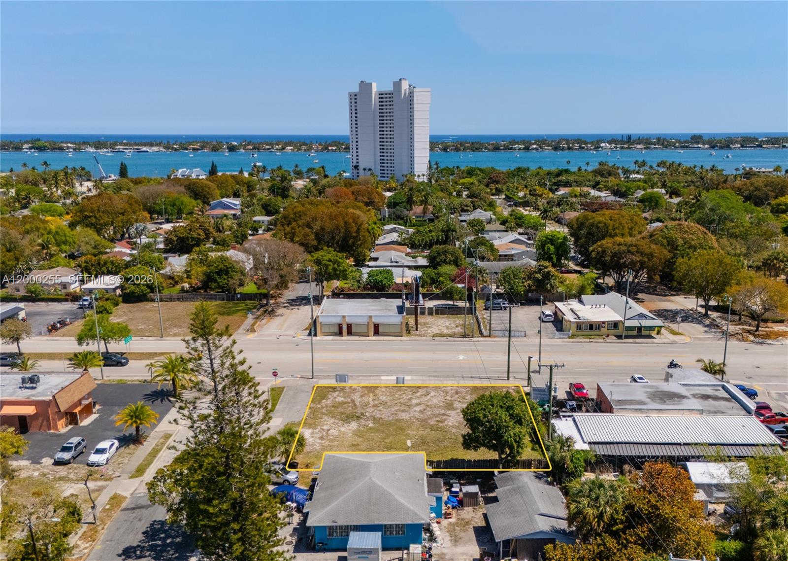An aerial view shows a vacant rectangular lot outlined in yellow near a coastal town — 5179 Broadway, West Palm Beach FL 33407, WEST PALM BEACH, FL