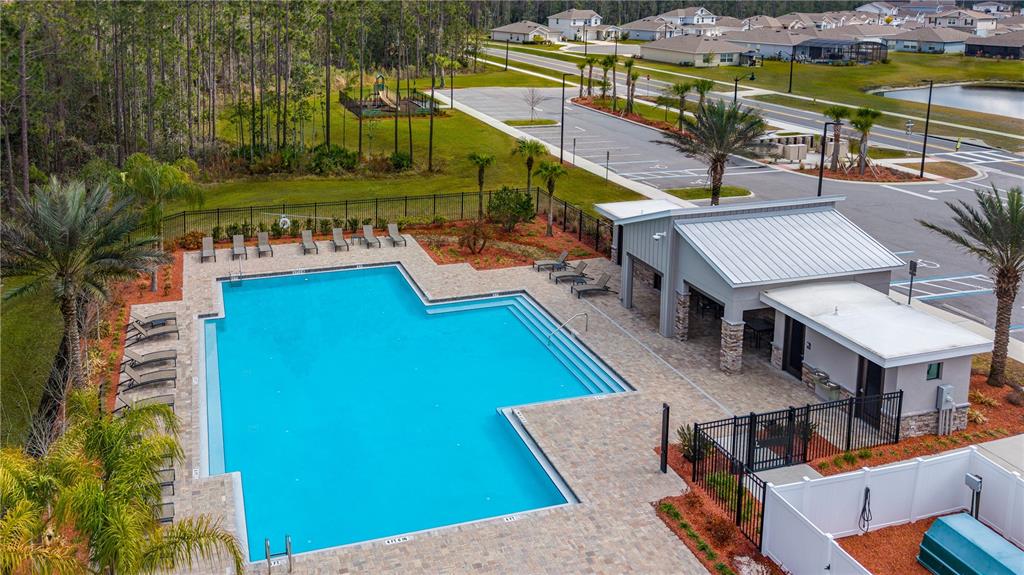 An aerial view shows a rectangular swimming pool with a surrounding patio and clubhouse building — 1192 BELLE ISLE LANE, DAYTONA BEACH, FL