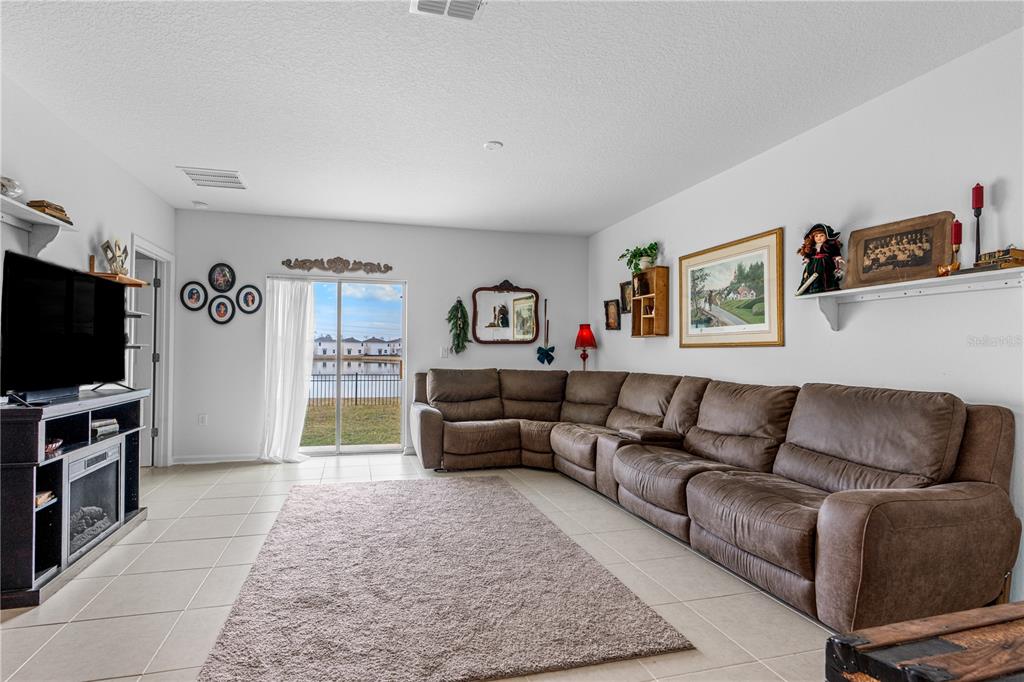 A living room features a large brown sectional sofa, a fireplace console, and sliding glass doors — 1192 BELLE ISLE LANE, DAYTONA BEACH, FL