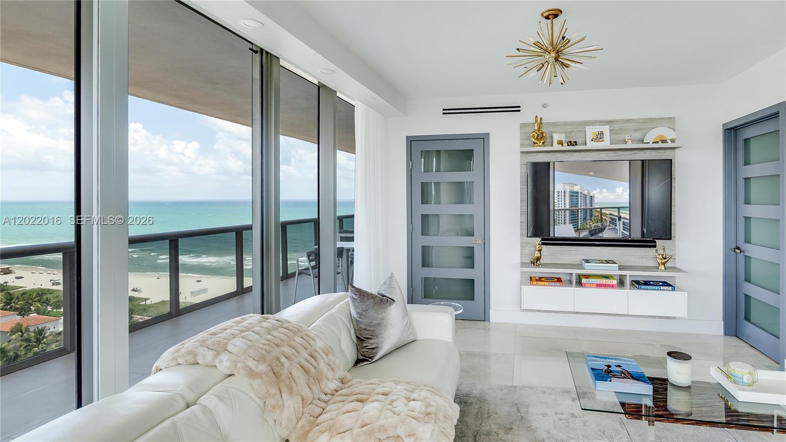 A modern dining room features a glass table, acrylic chairs, and a balcony with water views — 5875 Collins Ave # 1807, Miami Beach FL 33140, MIAMI BEACH, FL